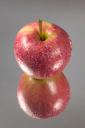 Red apple covered in droplets reflected on mirror cardの写真素材