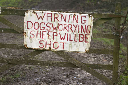 Sign on an old farm gate about dogs and sheepの写真素材