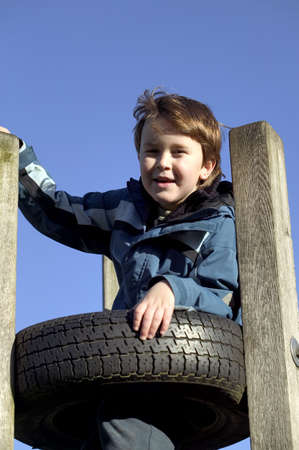 A young boy climbing a tyre tower in the park playgroundの写真素材