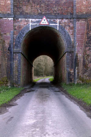 Road going under an old brick railway tunnelの写真素材
