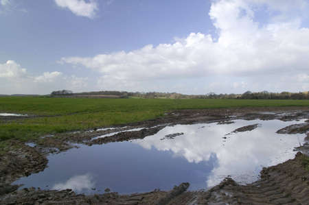 Rural Landscape with the sky reflected in a puddleの写真素材