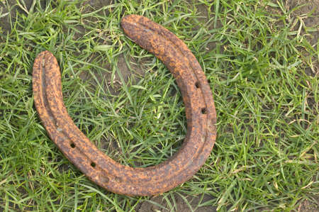 Old rusted horseshoe lying on a grass and mud background.の写真素材