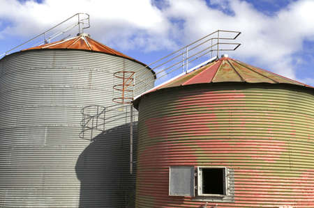 Pair of old grain drying silo's against a blue cloudy skyの写真素材