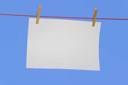 Blank horizontal paper on a washing line against a blue sky.の写真素材