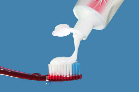 Toothpaste being applied to a red toothbrushの写真素材