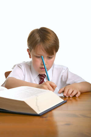 Schoolboy doing his homework, isolated against a white background.の写真素材