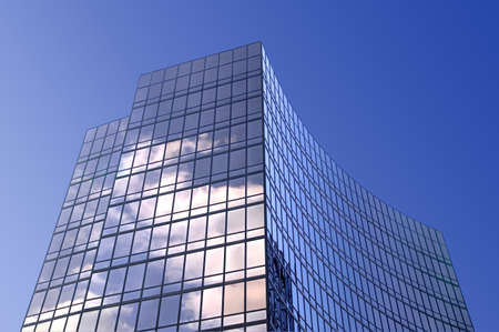 Modern smoked glass office building set against a blue sky.