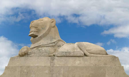 Stone lion statue against a blue cloudy sky.の写真素材