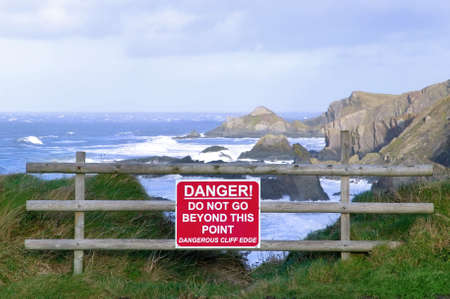 Dangerous cliff edge with warning sign.の写真素材