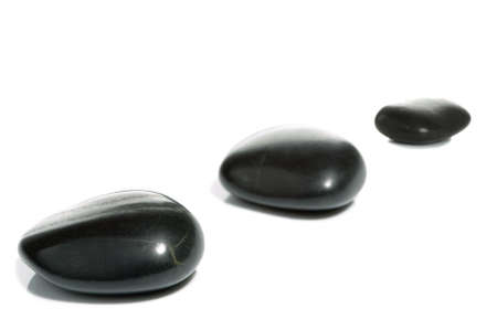 High key shot of three black pebbles on a white surface.の写真素材