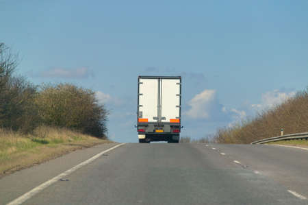 A heavy goods lorry disappearing over the brow of a hill.の写真素材