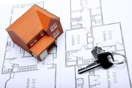 A model home and house key on architectural floor plans for an extension.