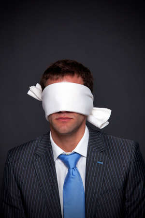 Businessman wearing a blindfold on a dark background with copy space.の写真素材