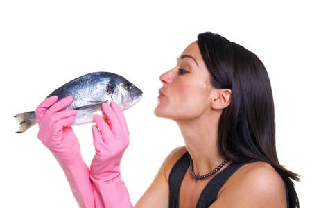 Woman in pink rubber gloves about to kiss a fish, isolated on white background.の写真素材