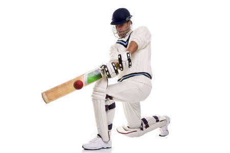 Cricketer down on his knee playing a shot, studio shot on white background.の写真素材