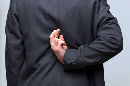 Businessman with his fingers crossed behind his backの写真素材