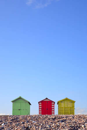 Three colourful beach huts against a bright blue sky, framed to allow copy space in the upper part of the image.の写真素材