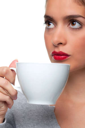 A woman holding a white cup about to drink some tea as she is thinking about something, white background. の写真素材