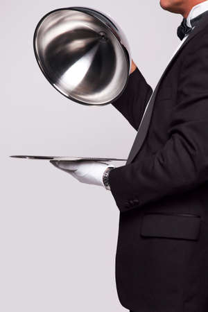 Butler lifting the cloche from a silver serving tray, insert your own object onto the tray.の写真素材