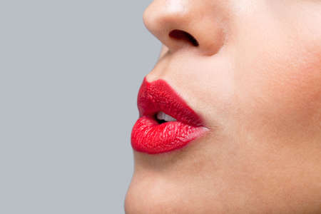 Close up of a womans face with red lipstick on blowing a kissの写真素材