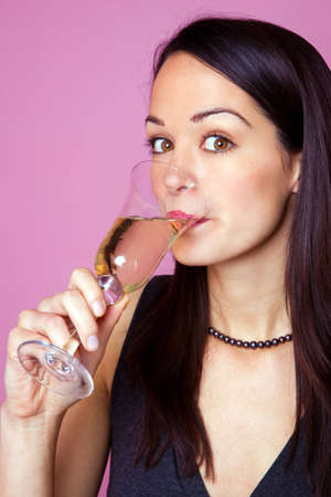 A brunette woman drinking a glass of champagneの写真素材