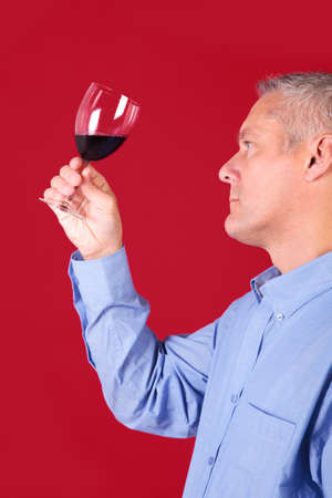 Man checking a glass of red wine for clarity and qualityの写真素材