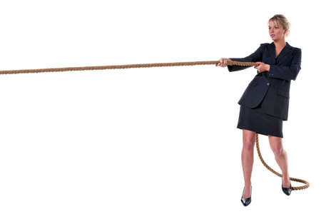 A blond businesswoman pulling on a long piece of rope, isolated on a white background.の写真素材