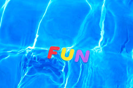 The word FUN made from foam letters floating on the water surface of a swimming poolの写真素材