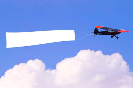 An airplane flying through the sky pulling a blank white banner to add your own message.の写真素材