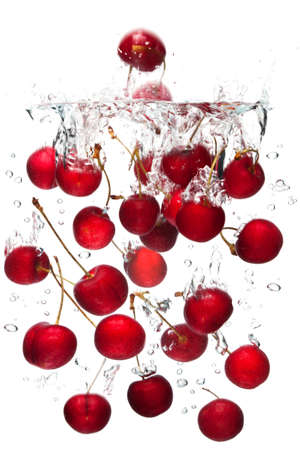 red cherries falling into water with a white background.