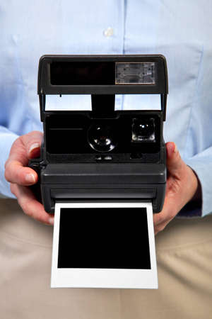 Photo of a woman holding an instant camera with a blank print to add your own image,clipping path included for the empty space.の写真素材
