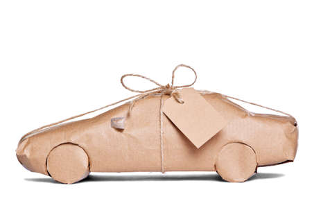 Photo of a car wrapped in brown recycled paper with label, cut out on a white background.の写真素材