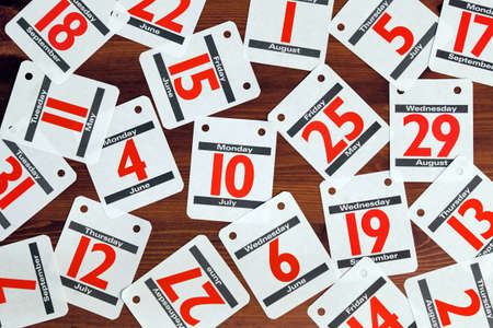 Photo of various calendar dates spread out on a wooden desk.の写真素材