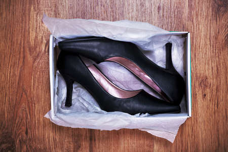  a pair of new womens court shoes in a shoe box on rustic wooden floor.の写真素材
