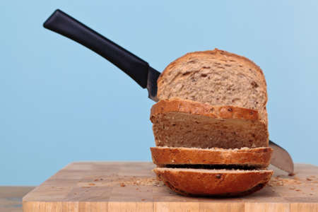 Wholemeal loaf of bread being sliced with a knife.の写真素材