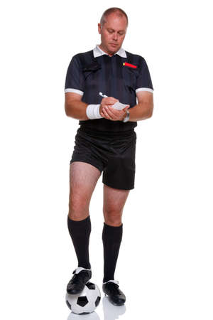 Full length photo of a football or soccer referee with ball writing in his report book, isolated on a white background.の写真素材