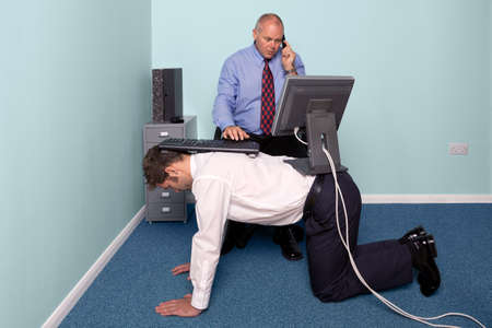 Photo of a businessman using a work experience employee for his deskの写真素材