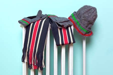 Photo of a mans hat, scarf and gloves drying on an old traditional cast iron radiator, good image for winter related themes.の写真素材