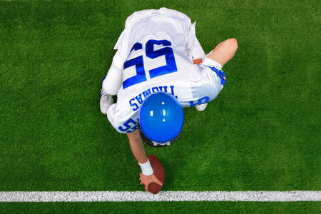 Overhead photo of an American football player center offense about to snap the ball. The uniform he's wearing is one I had made using my name and does not represent any actual team colours.の写真素材