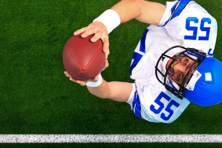 Overhead photo of an American football player wide receiver catching the ball in the air. The...