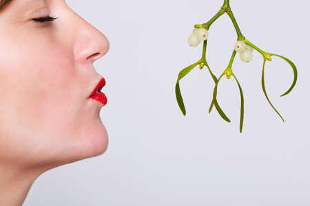 Photo of a woman with her eyes closed and red lipstick on waiting to be kissed under the mistletoe. の写真素材