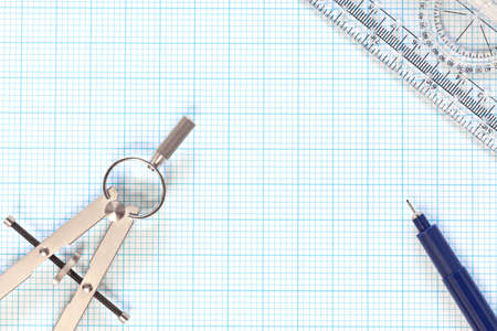 Still life photo of engineering graph paper with a fine 0 1mm pen, compass and protractor ruler, blank to add your own design, image or text の写真素材