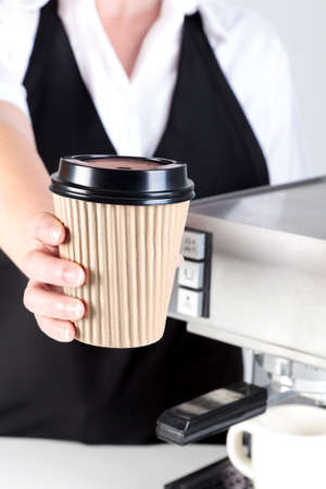 Photo of a Barista handing you a coffee in a disposable paper takeaway cup.の写真素材