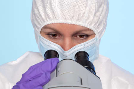 Photo of a biochemist looking through the eyepieces of a stereo optical laboratory microscope.