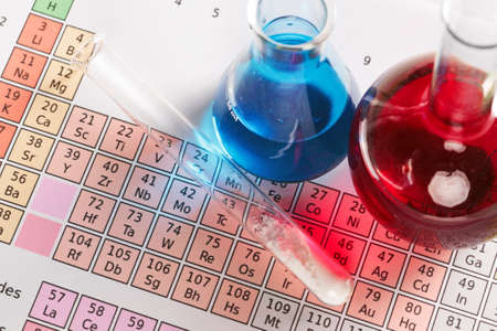 Photo of a periodic table of the elements with flasks and test tube containing chemicals both liquid and powder.の写真素材