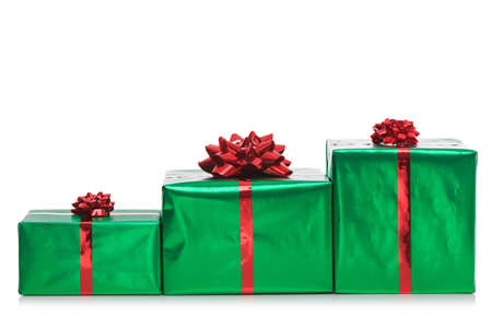 Three gift wrapped presents in green wrapping paper with red bow and ribbon, isolated on a white background.の写真素材