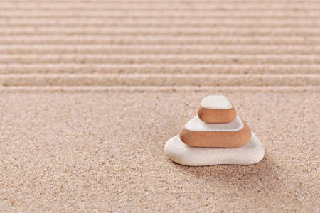 Three pebbles stacked on a raked sand zen garden.の写真素材