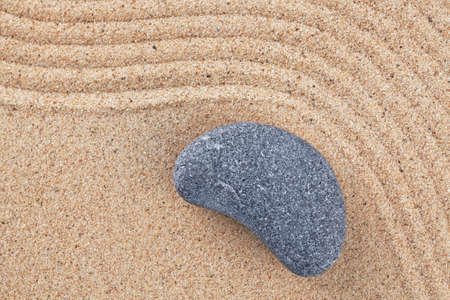 A curved pebble on a raked sand zen gardenの写真素材