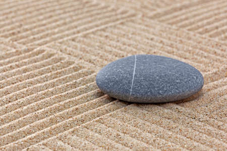 A pebble on a raked sand zen garden with patchwork patterns.の写真素材