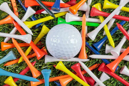 A golf ball amongst a collection of coloured wooden tees.の写真素材